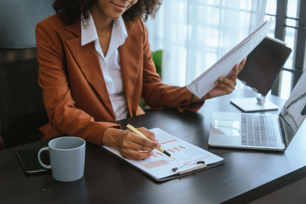 Analista calculando superávit en computadora con hojas de cálculo y gráficos económicos en oficina